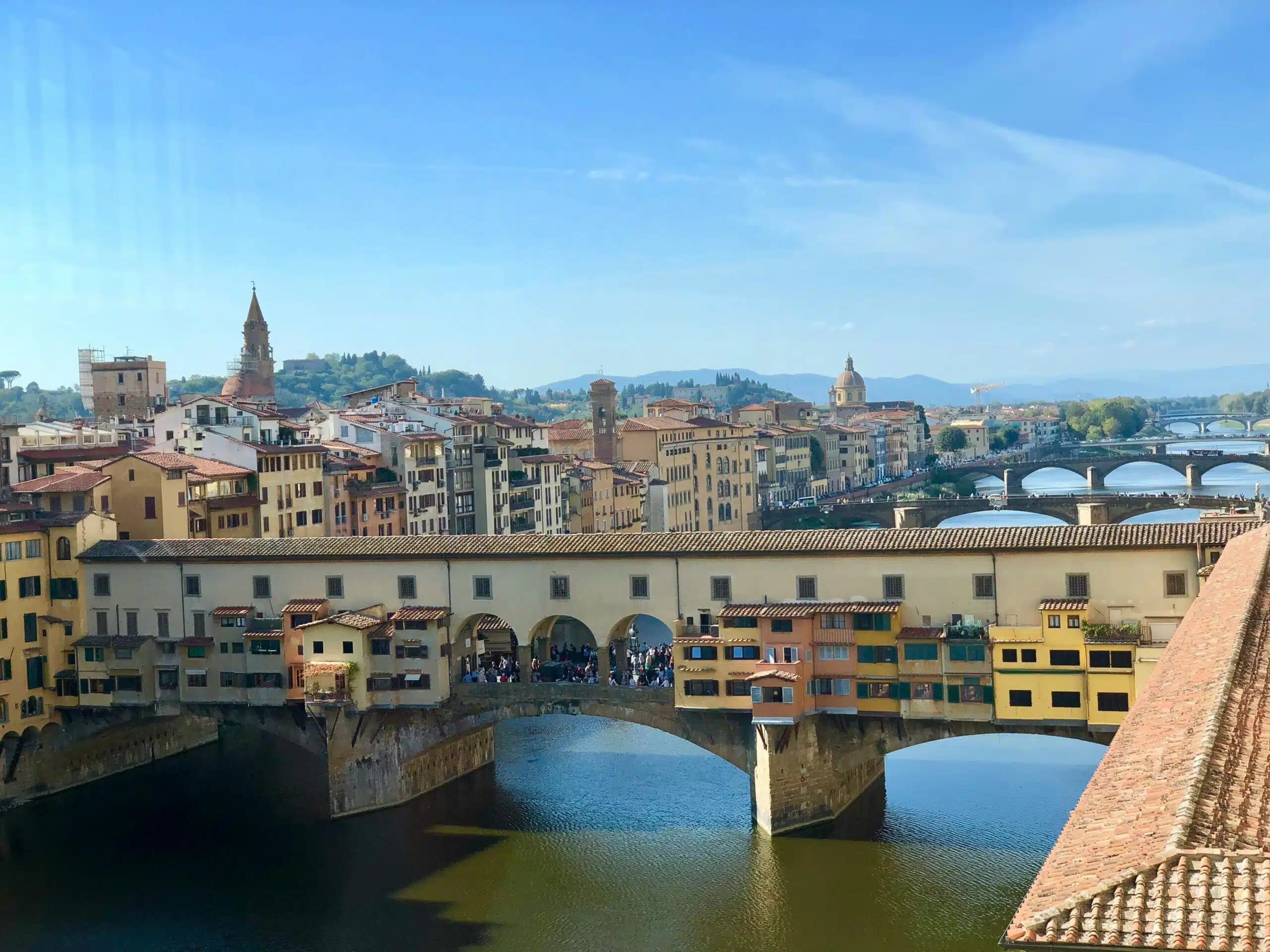 The Ponte Vecchio spanning the Arno in Florence, with the city rooftops and hills behind it