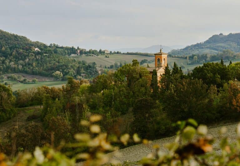 Autumn hills outside Bologna with an ochre church bell tower rising above the trees