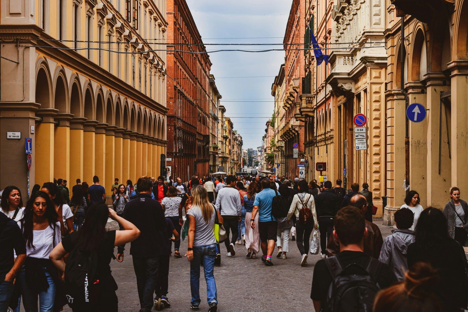 Pedestrians walking along a busy street lined with arcaded buildings in central Bologna